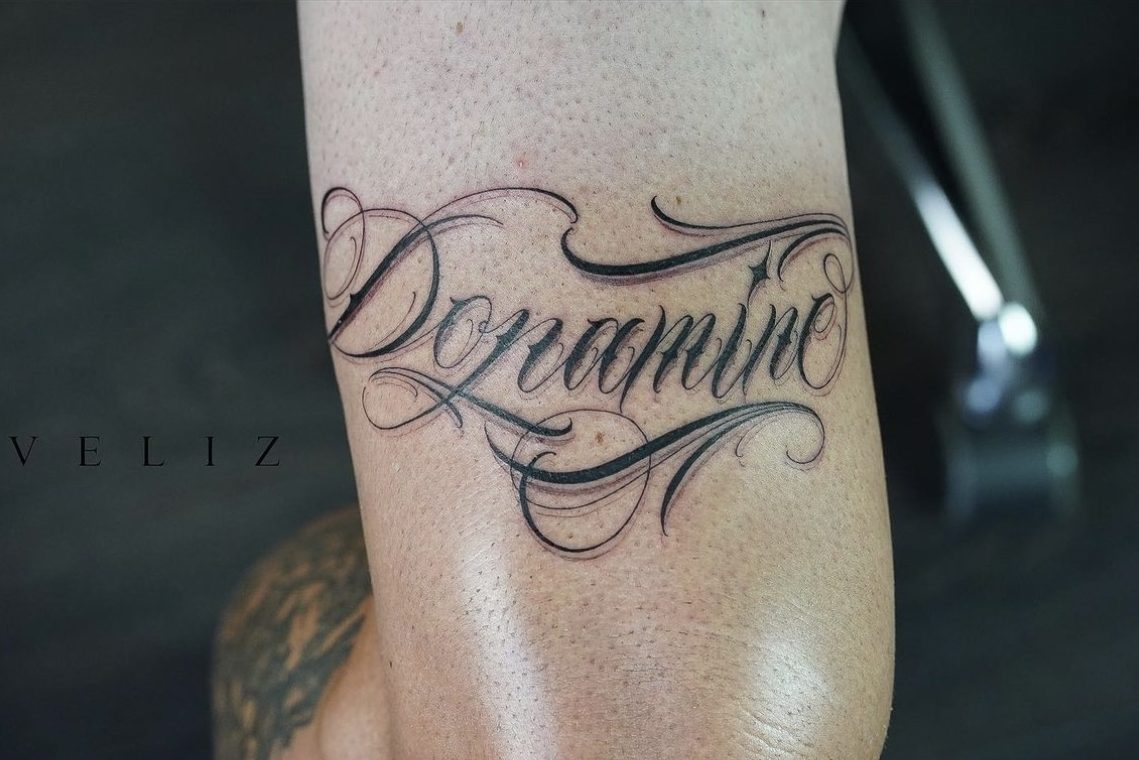 Dopamin custom skrevet på låret. tatoveirngen tatt hos Attitude tattoo studio