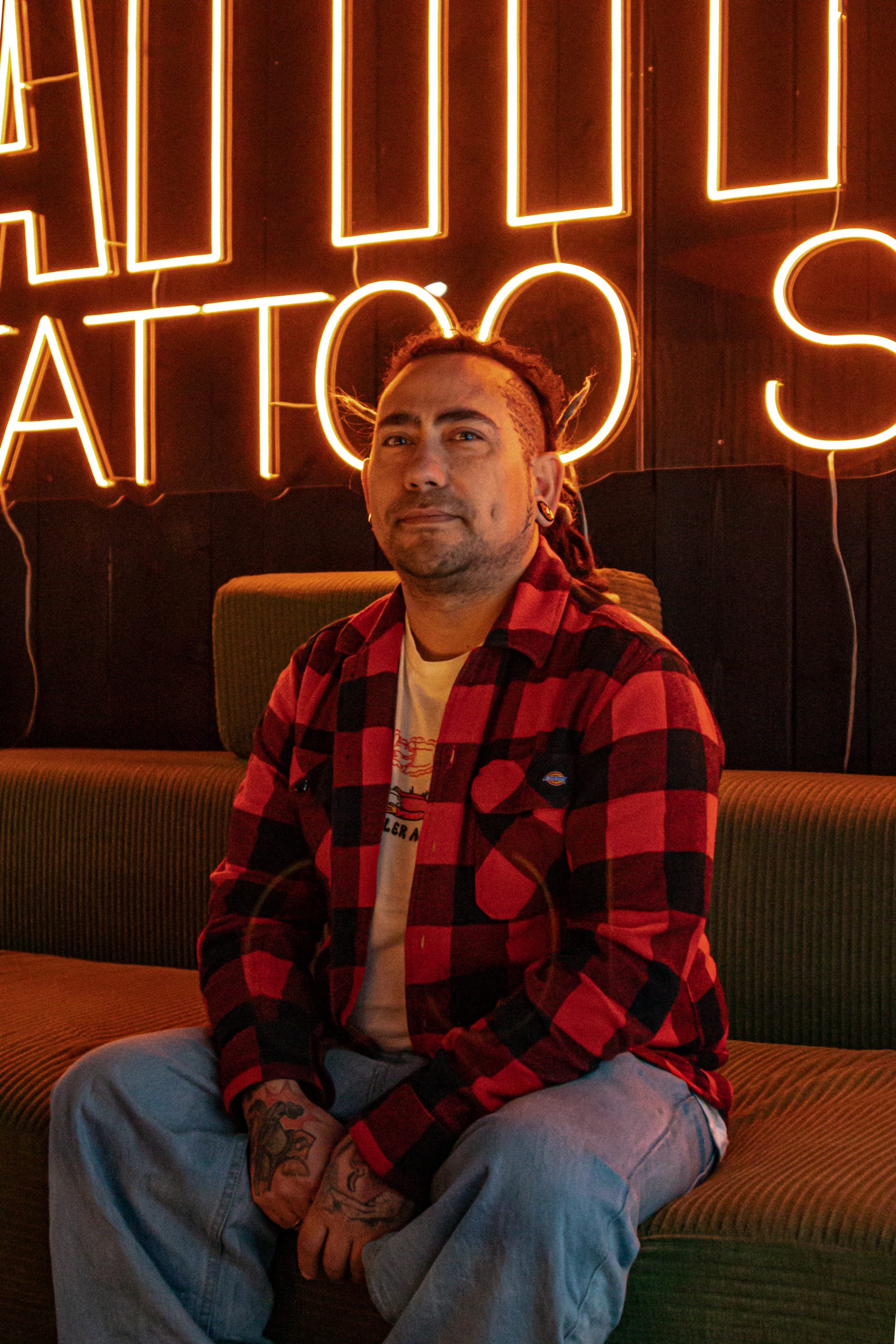 Manuel sitter i en grønn sofa hos Attitude tattoo studio